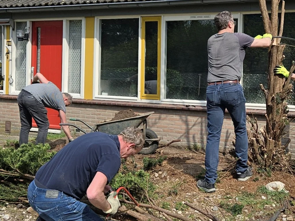 Vrijwilligers van Stichting Present en Studio FERM werken samen aan de aanleg en het onderhoud van een tuin
